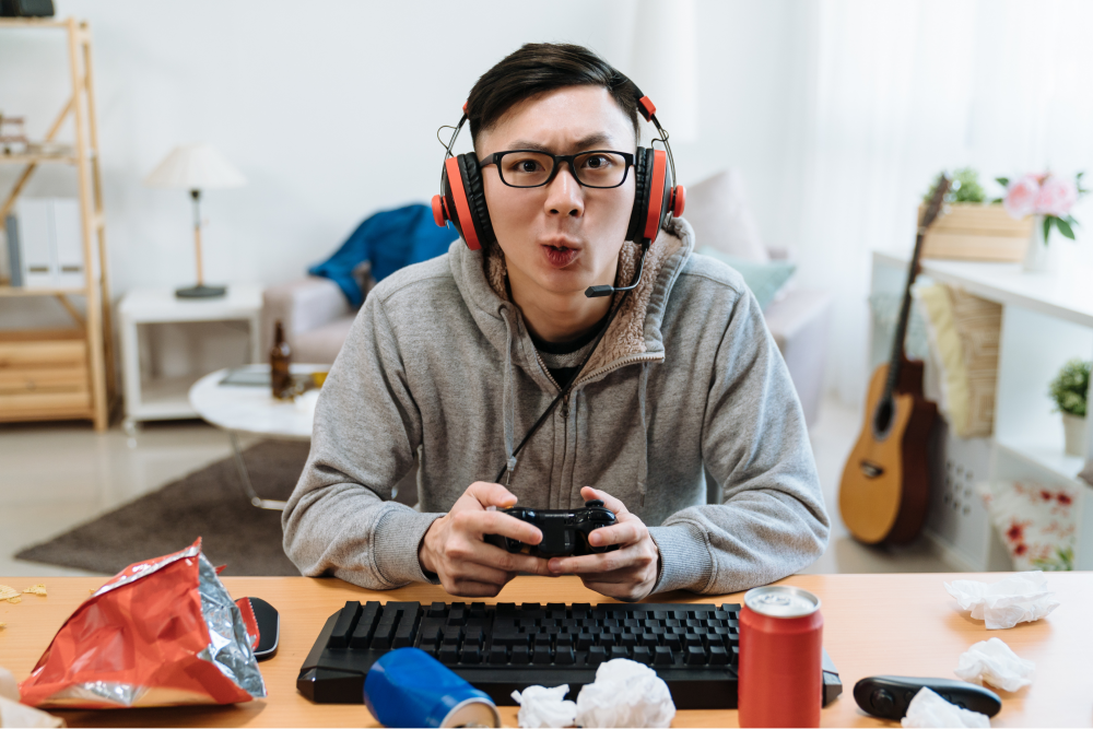 an avid gamer surrounded by food wrappers on their desk